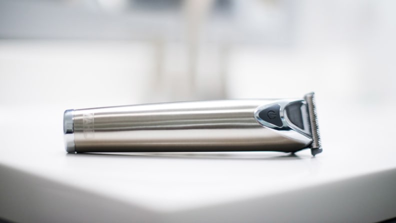 A stainless steel beard trimmer lays on a sink.