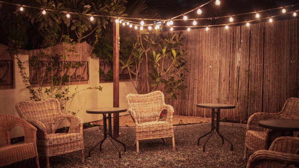 A backyard decorated with chairs and outdoor string lights.