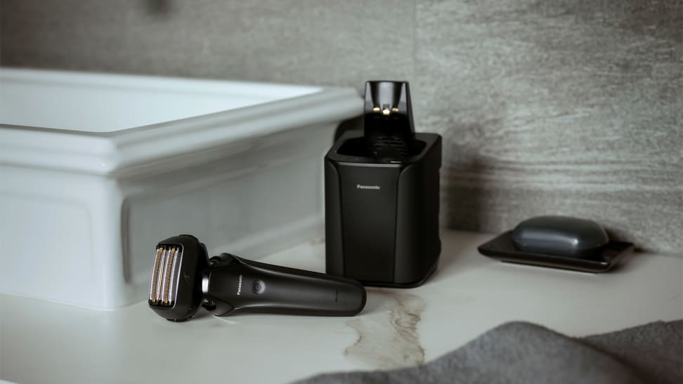 The Panasonic Arc6 electric shaver laying on a sink with its charging dock behind it.