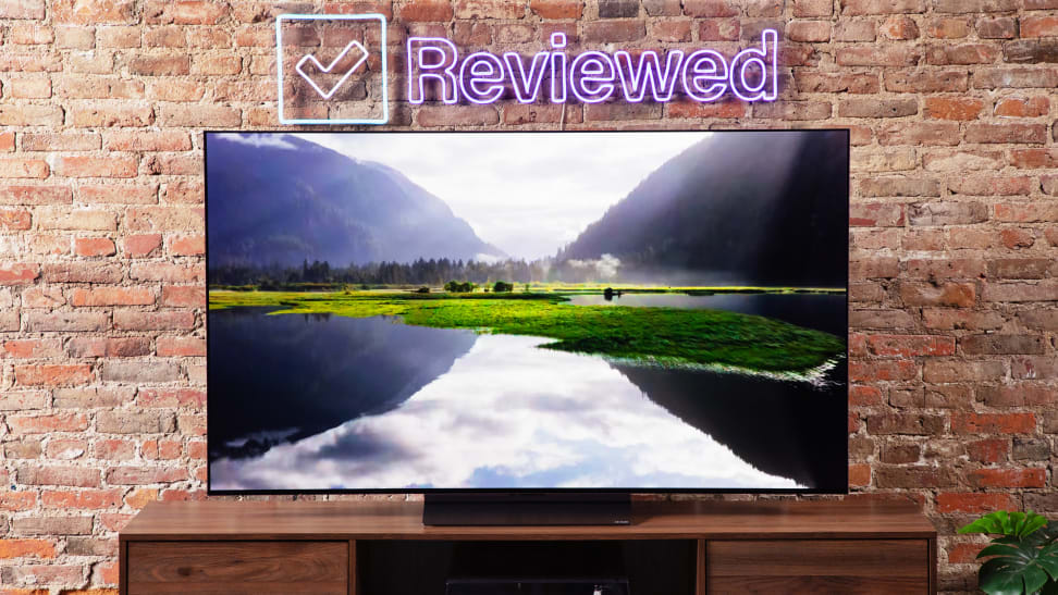 The LG C3 OLED TV in front of a brick wall with the Reviewed sign above.