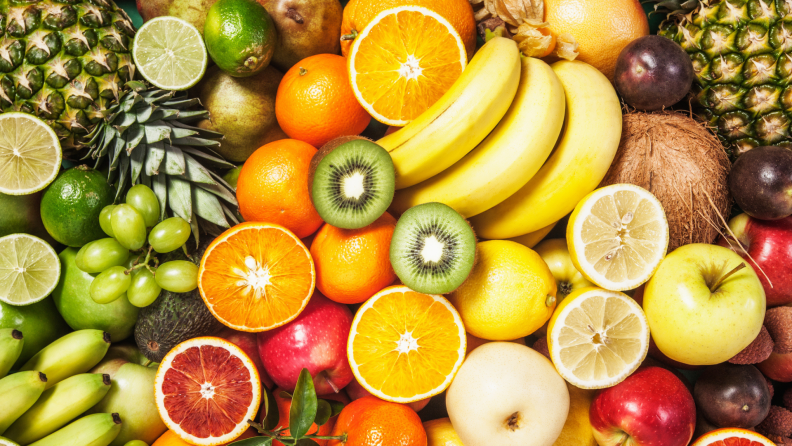 Big platter of fruit with strawberries, pears, coconuts, lemons, kiwis, grapefruits, bananas, plums, apples, limes, grapes, oranges and pineapples.