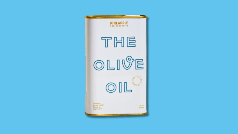 Gold and white tin of Pineapple Collaborative's The Olive Oil in front of blue background.