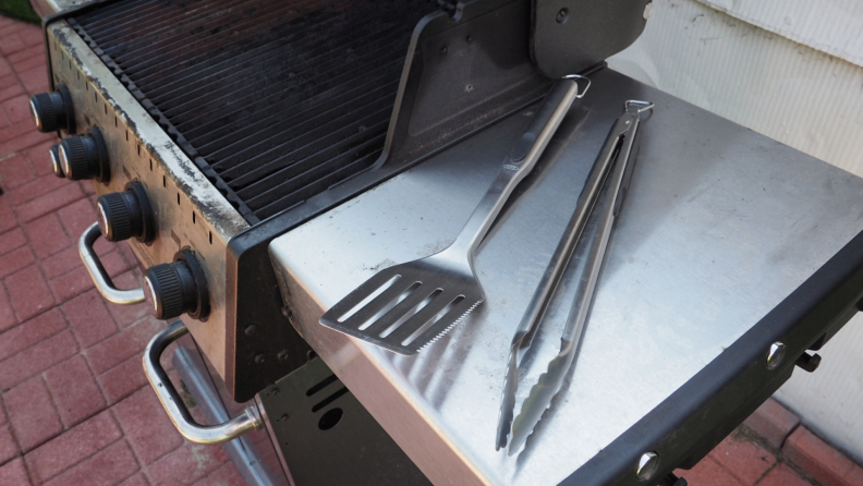 OXO grill tongs and spatula on a grill.