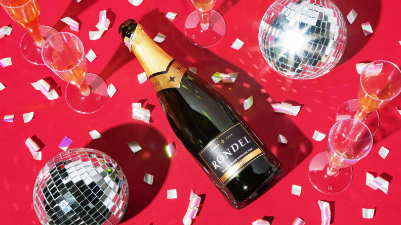 A bottle of Rondel Nonalcoholic Cava on a red background with confetti and disco balls.