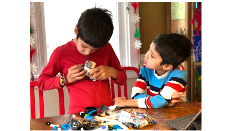 Two boys assemble a LEGO BOOST kit