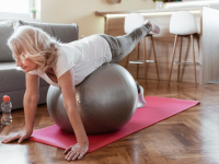 A person balances on a fitness ball in their living room during a workout.