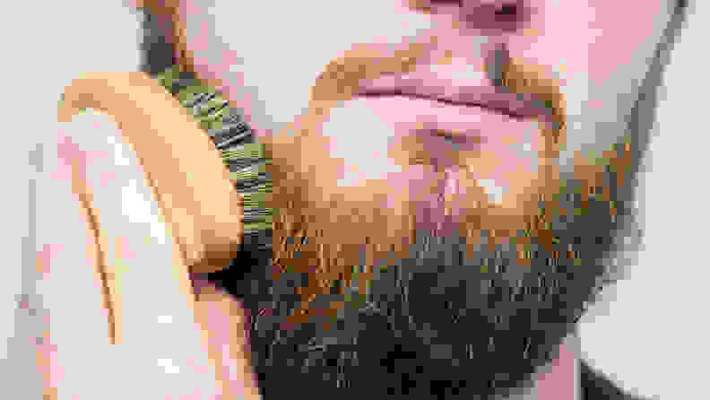 Close-up: an individual brushes their beard.