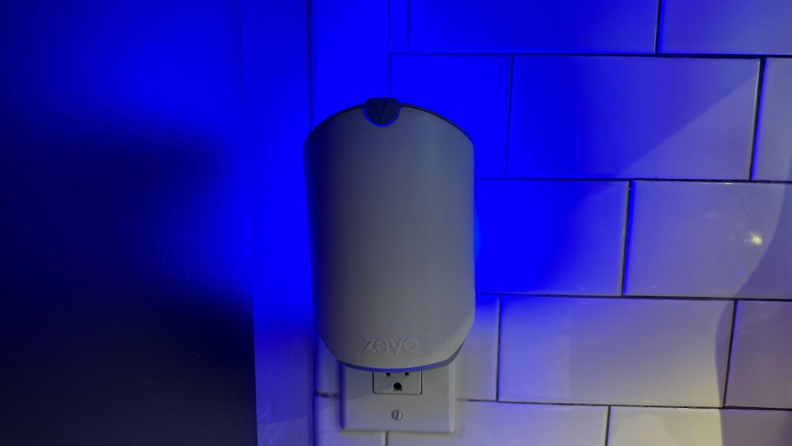 The Zevo Fly Trap plugged into an electrical outlet in a kitchen. Shown emitting a blue light.