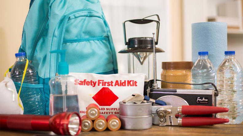 Hiking essentials like food, first-aid supplies, and a lantern laid out on a table.