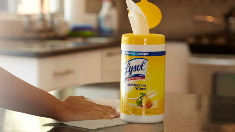 A person using a Lysol wipe on a kitchen counter.