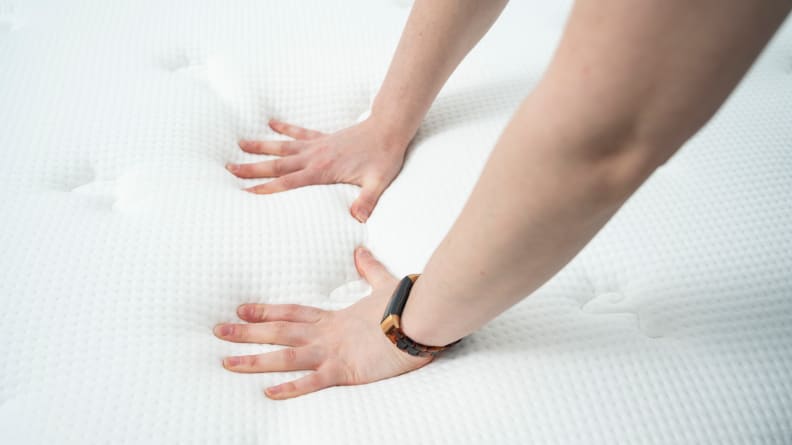 a woman's hands press into the surface of the Brooklyn Bedding Signature Hybrid