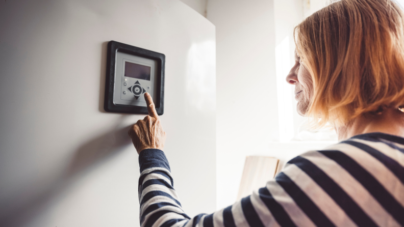 A person sets their thermostat.