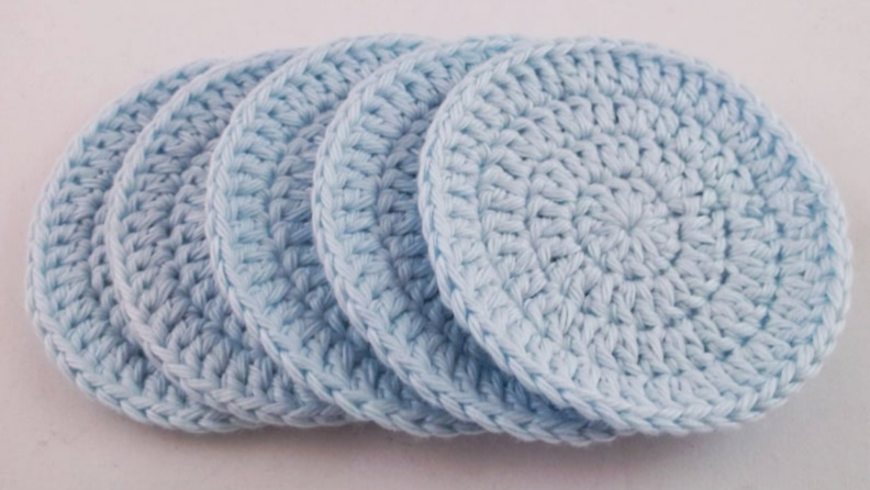 5 baby blue crocheted face scrubbies lined up.