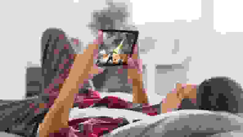 Man lying on bed, watching Samsung tablet.