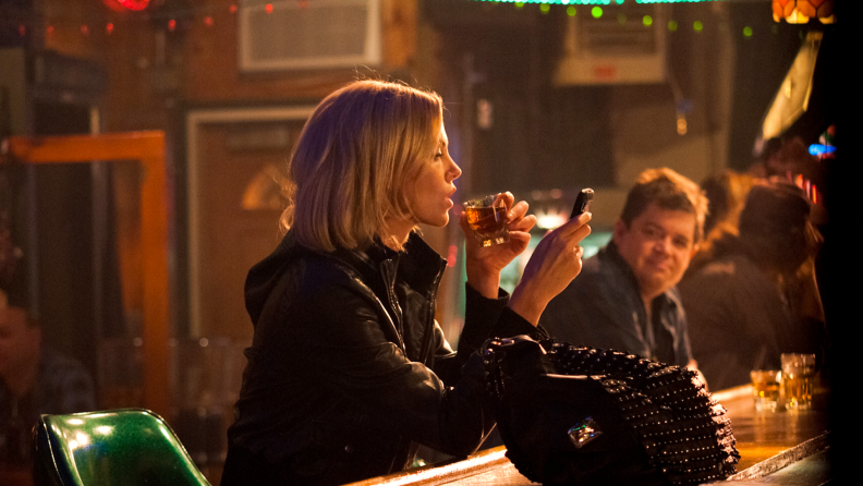Actors Charlize Theron and Patton Oswalt sit drinking at a small-town bar in the 2011 film Young Adult.