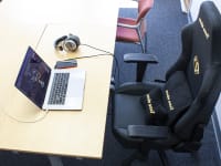 The AndaSeat Phantom 3 gaming chair placed in front of an office desk with a laptop and a pair of headphones.