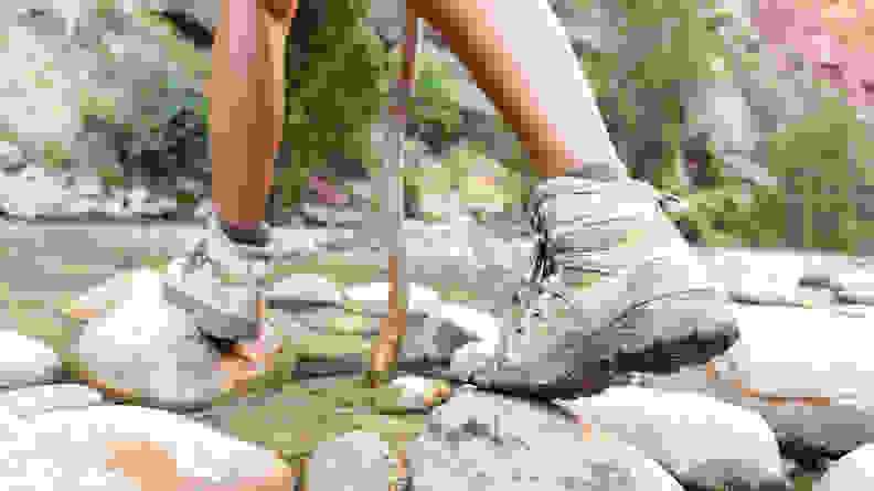 A close-up of a person wearing hiking boots crossing a stream.