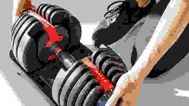 A woman adjusting the weight on the Bowflex adjustable dumbbells.