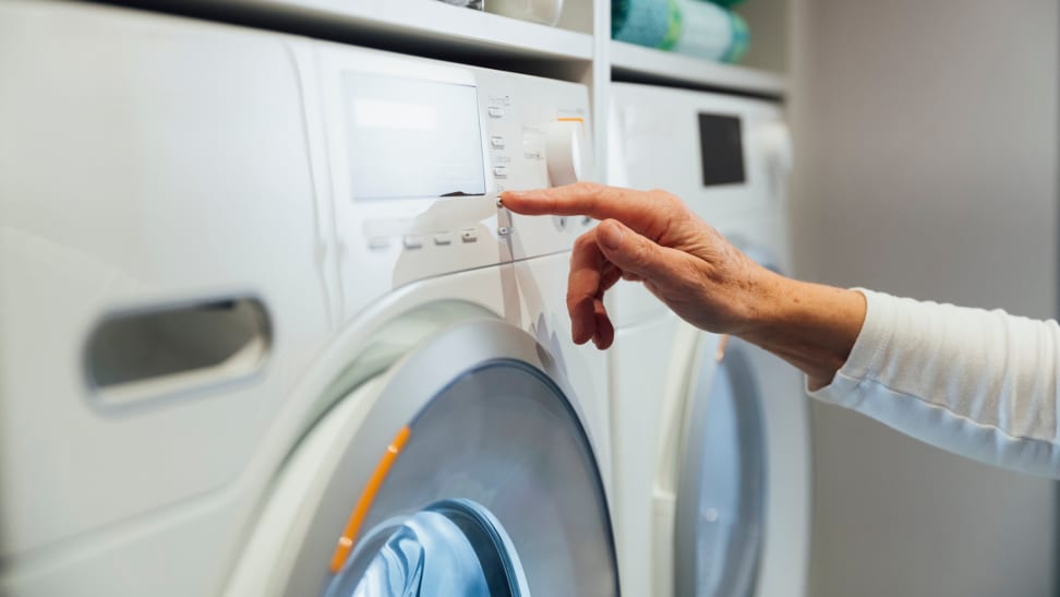 Person pressing buttons on washer machine.