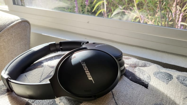 The Bose QC45 headphones sitting atop a pillow in front of a window