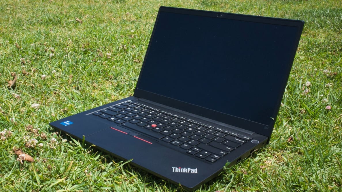 An open laptop resting on a field of grass.