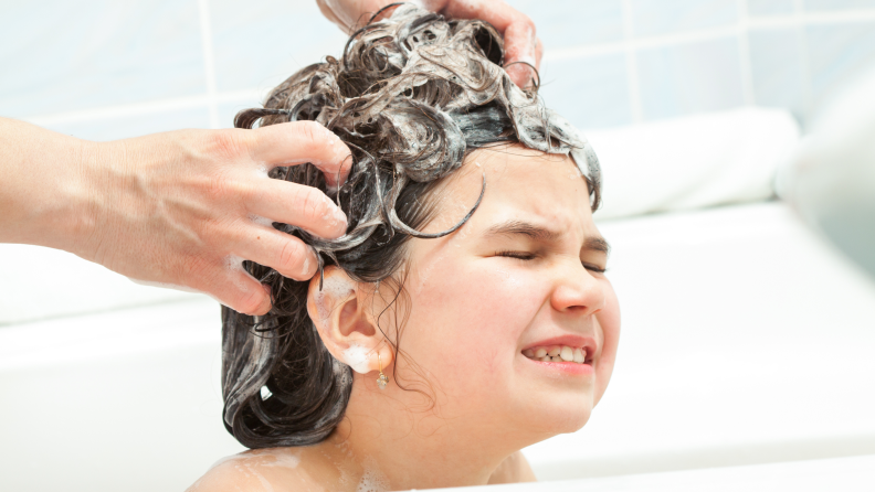 A child has their hair scrubbed with suds.