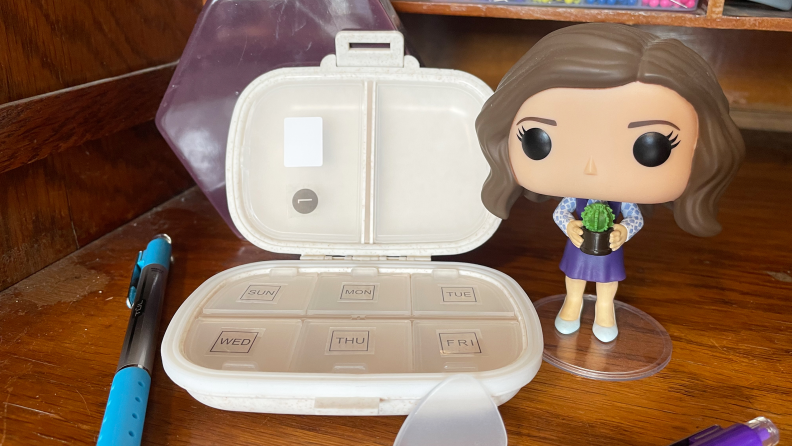 The Holii Travel Pill Organizer next to a Funko Pop figurine