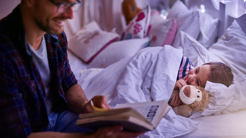 A father reads a bedtime story to his daughter.