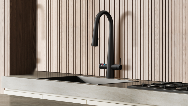 The curved faucet of the Zip Water HydroTap Celsius Plus All-in-one with Pull-down Sprayer and Zip Reel above a sink in front of a striped wall.