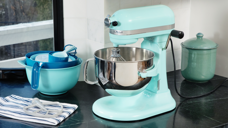 A teal KitchenAid 600 sits on a black counter with blue mixing bowls and a cookie jar.