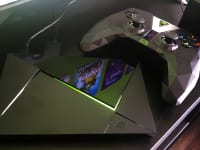 A game controller sitting next to a small TV streaming box
