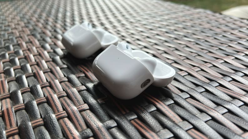 The AirPods Pro old and new sit open in their white cases on a braided cable, shot from the side.