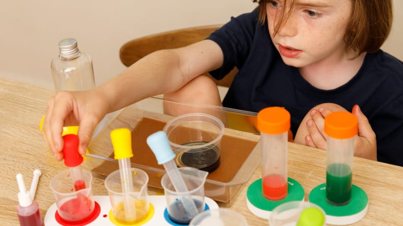 A boy plays with a water and oil experiment, using test tubes and vials.