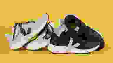 Two white running shoes stacked against a pair of black running shoes.