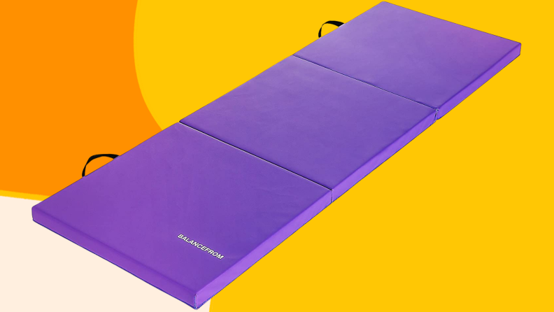 A purple yoga mat laid out against yellow and orange background.