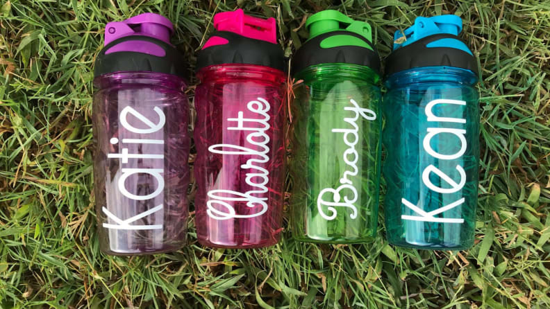 Four water bottles with names printed on them in white paint.