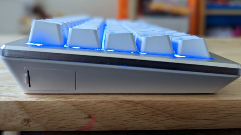 A close up view of the side of a white keyboard with glowing blue keys