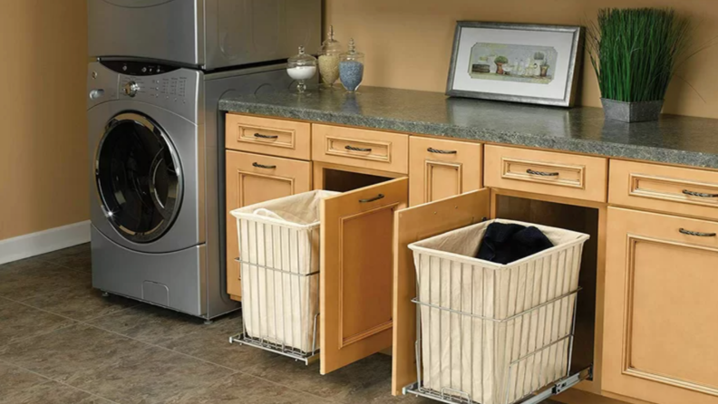 Sliding hamper in cabinets within laundry room at home.