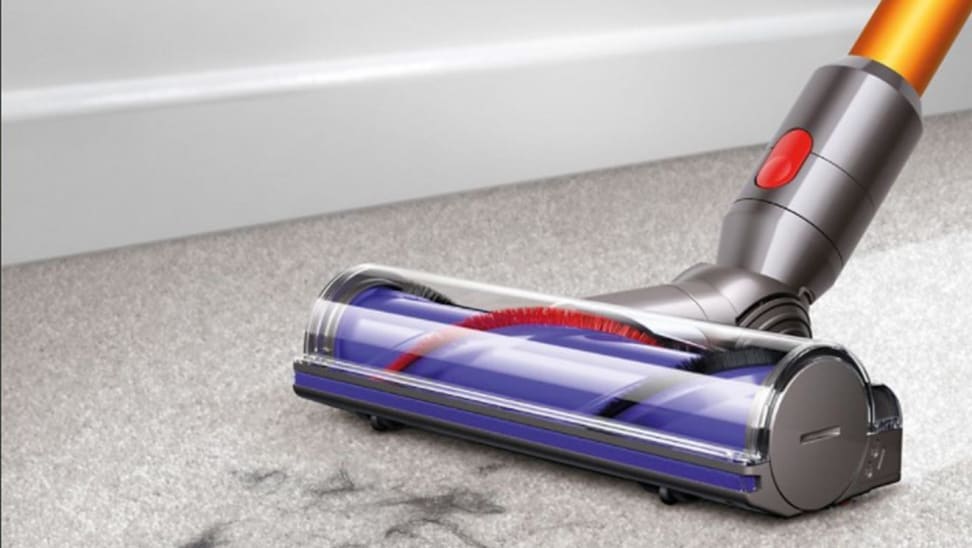 A Dyson vacuum cleans a dirty carpet.