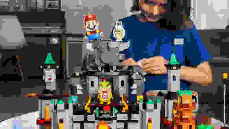 A setup of the Bowser's Castle Boss Battle expansion set, with a child building in the background.