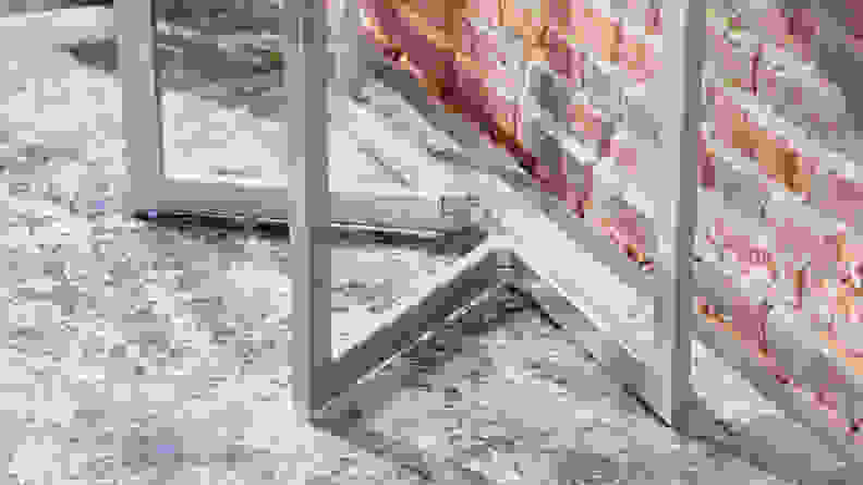 The metal legs of the Expand Furniture Mini Flip shown against a brick wall with a blue carpet underneath