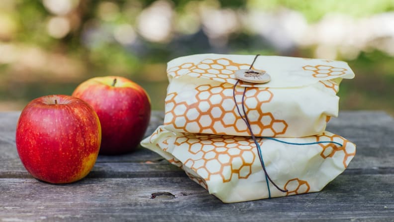 Two apples next to two sandwiches wrapped in bee's wrap