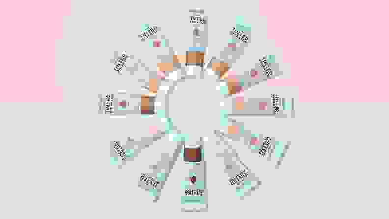 All of the shades of the Wet n Wild Bare Focus Tinted Hydrator are in a circle with a pink and blue background behind them.