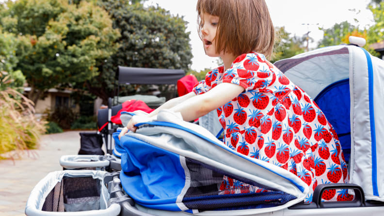 A small child standing in a Gladly Anthem2 stroller and playing with the canopy.