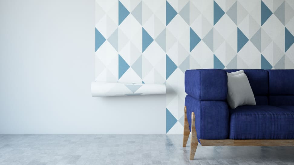 Geometric wallpaper pasted on wall with a blue couch in front of the wall.