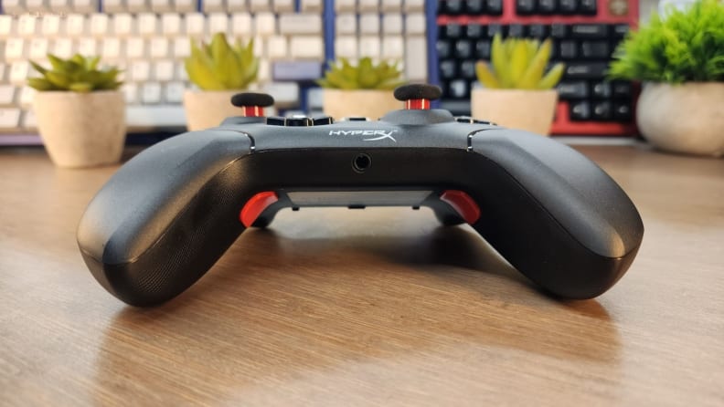 The HyperX Clutch Gladiate controller in the color black on a wooden table.