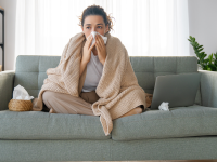 Person on couch blowing nose