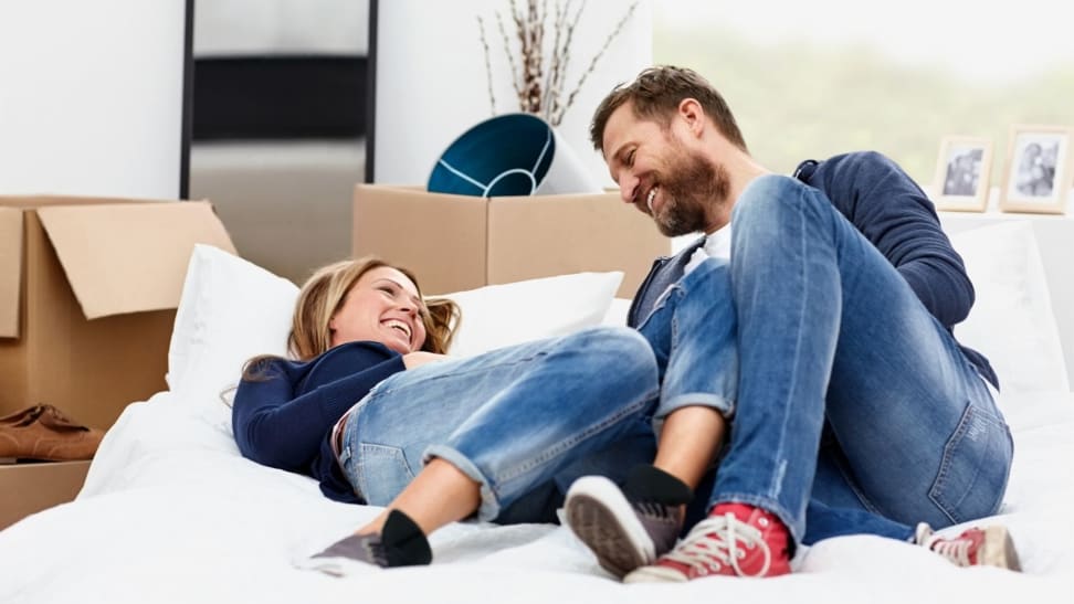 a couple lying on a new mattress surrounded by moving boxes