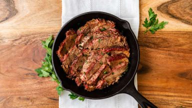 Cast iron skillet filled with sliced beef on a table