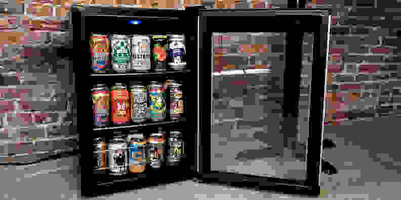 The Wine Enthusiast Evolution Series Beverage Center, sitting against a brick wall with its door open, showcasing a bunch of beer inside.